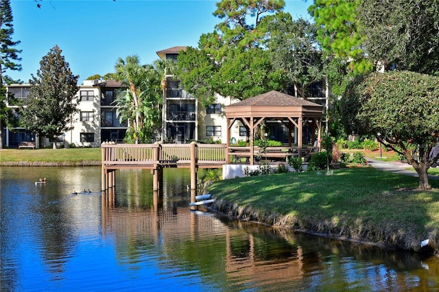 view of dock with a gazebo, a yard, and a water view