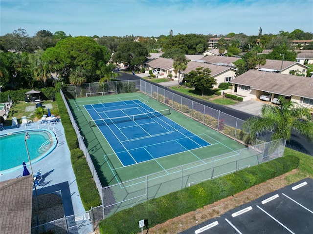 view of tennis court with a community pool and fence