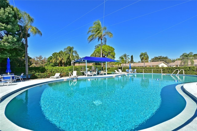 community pool with a patio area and fence