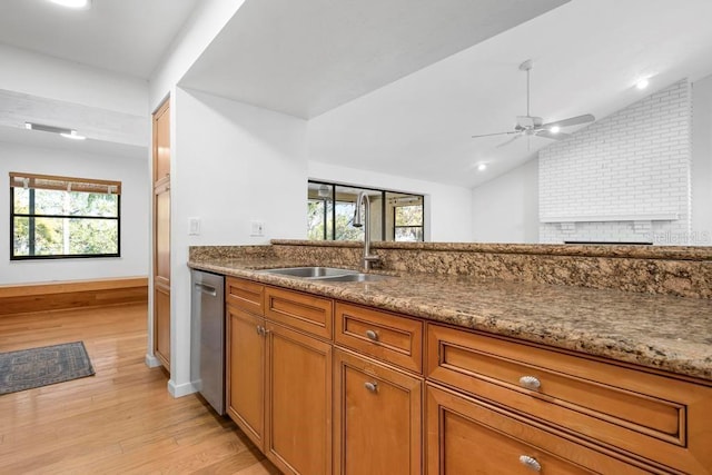 kitchen featuring a sink, light wood-style floors, brown cabinetry, lofted ceiling, and dishwasher