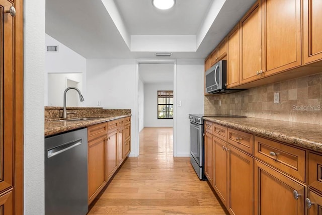 kitchen with tasteful backsplash, visible vents, brown cabinets, appliances with stainless steel finishes, and a sink