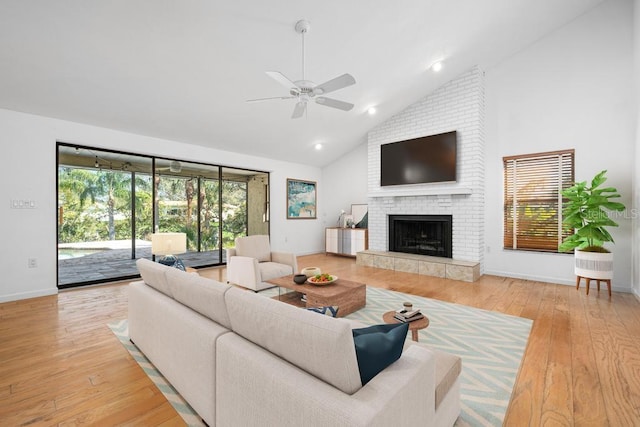 living area featuring a brick fireplace, plenty of natural light, wood-type flooring, and high vaulted ceiling