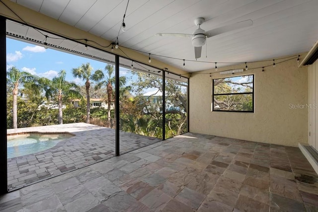 unfurnished sunroom featuring rail lighting and a ceiling fan