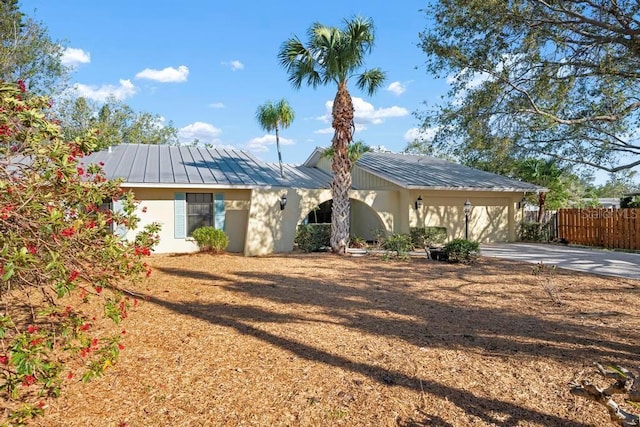 single story home with stucco siding, driveway, fence, an attached garage, and metal roof