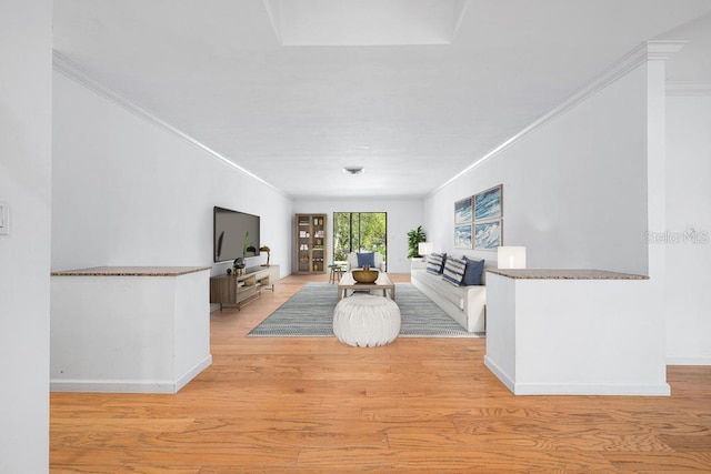 living area with baseboards, crown molding, and light wood finished floors