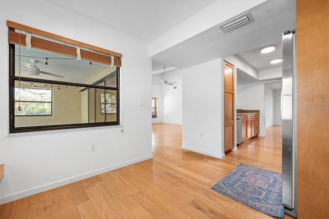 empty room with light wood-style flooring, baseboards, visible vents, and ceiling fan