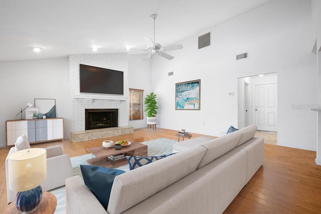 living area featuring a ceiling fan, a brick fireplace, wood finished floors, and visible vents