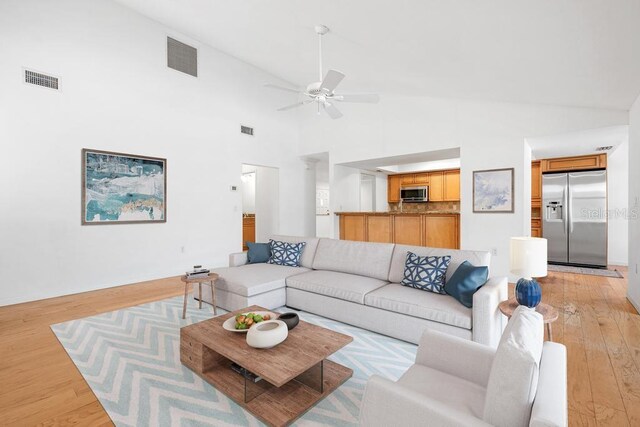 living room featuring visible vents, light wood-type flooring, and ceiling fan