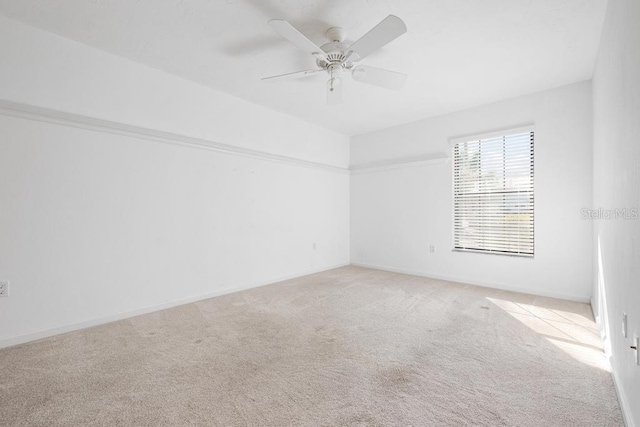 empty room featuring baseboards, carpet floors, and ceiling fan