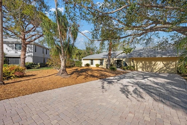 view of front facade with decorative driveway, a garage, and stucco siding