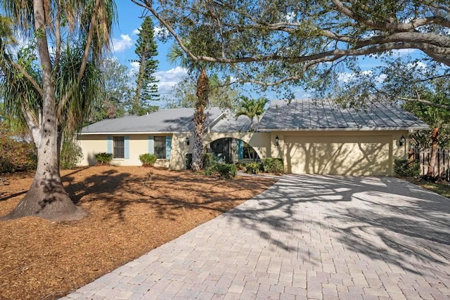 single story home featuring stucco siding, an attached garage, and decorative driveway