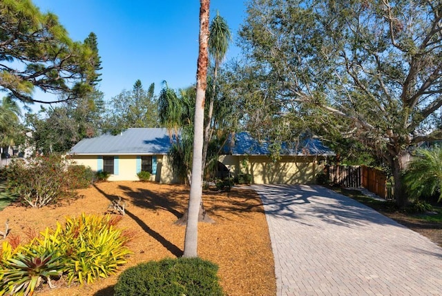 view of front of home featuring decorative driveway, fence, and stucco siding