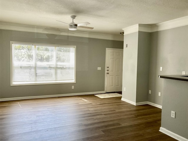 unfurnished room featuring ceiling fan, a textured ceiling, dark wood-style floors, and ornamental molding