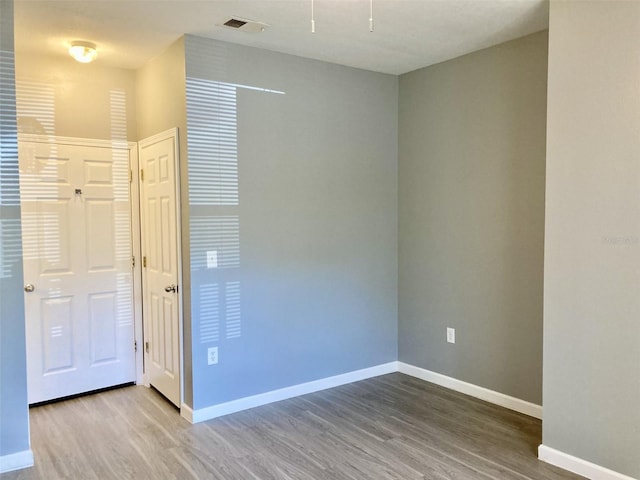 spare room featuring visible vents, baseboards, and wood finished floors