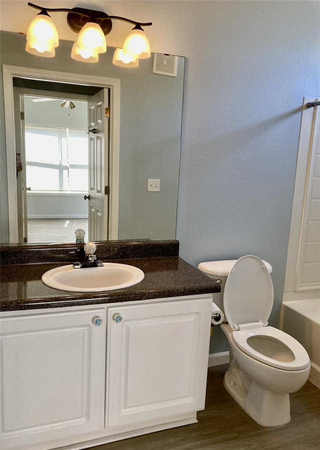 full bath featuring toilet, wood finished floors, vanity, and a washtub