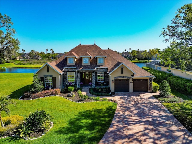 view of front of property with a front lawn, decorative driveway, stone siding, and an attached garage