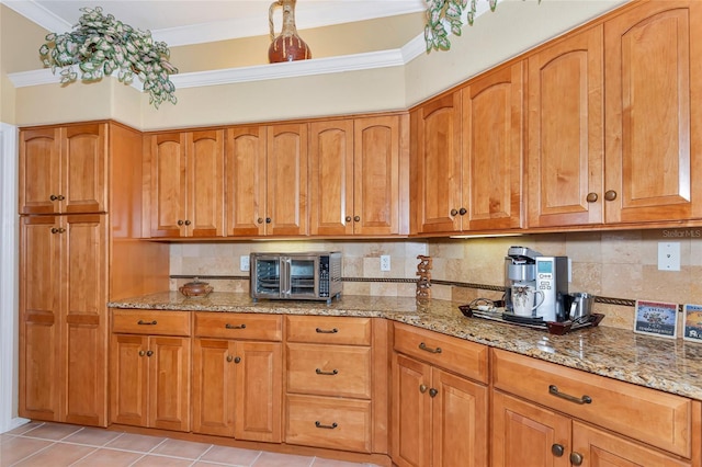 kitchen featuring light stone counters, decorative backsplash, and crown molding