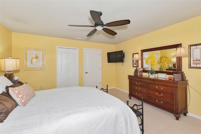 bedroom featuring visible vents, baseboards, ceiling fan, a closet, and light carpet