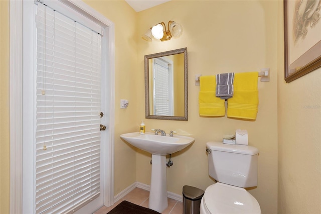 half bathroom with baseboards, toilet, and tile patterned flooring