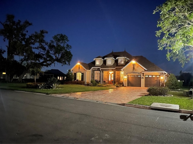 view of front of home featuring a garage, decorative driveway, and a lawn