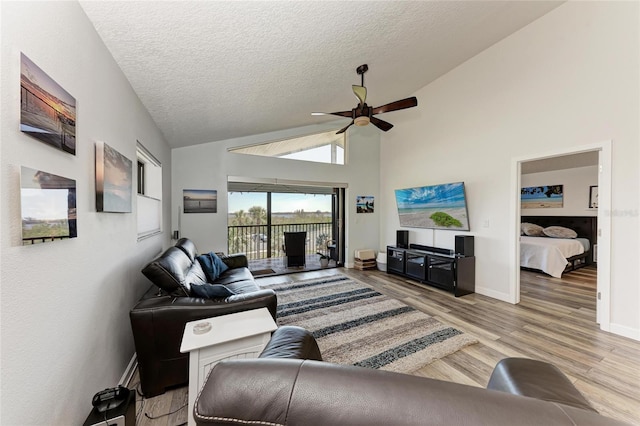 living area featuring wood finished floors, a ceiling fan, baseboards, high vaulted ceiling, and a textured ceiling