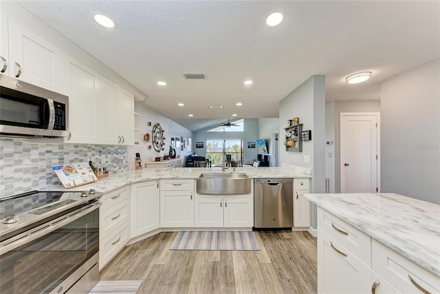 kitchen with tasteful backsplash, visible vents, light wood-style flooring, appliances with stainless steel finishes, and a sink