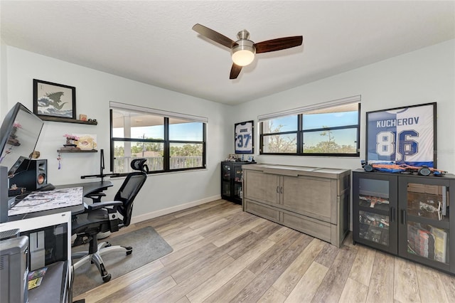 office area with light wood-type flooring, baseboards, a textured ceiling, and a ceiling fan