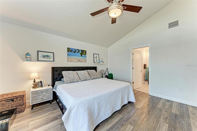 bedroom with lofted ceiling, light wood-style floors, visible vents, and a textured ceiling