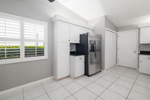 kitchen featuring white cabinetry, dark countertops, light tile patterned floors, and stainless steel refrigerator with ice dispenser