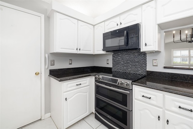 kitchen with black microwave, dark stone counters, range with two ovens, light tile patterned floors, and white cabinets