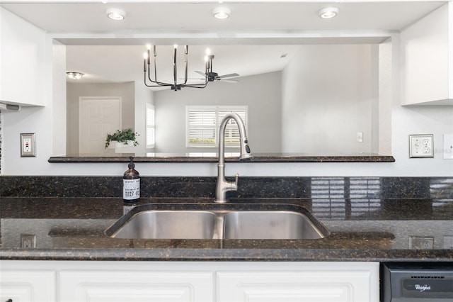 kitchen with a sink, dishwasher, white cabinets, and dark stone countertops