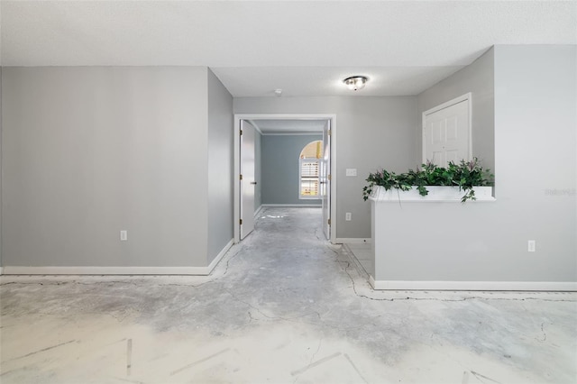 hallway with baseboards and a textured ceiling