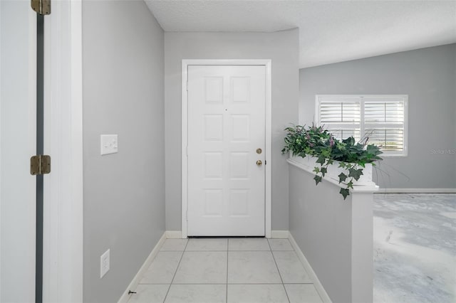 doorway with light tile patterned floors, baseboards, and a textured ceiling