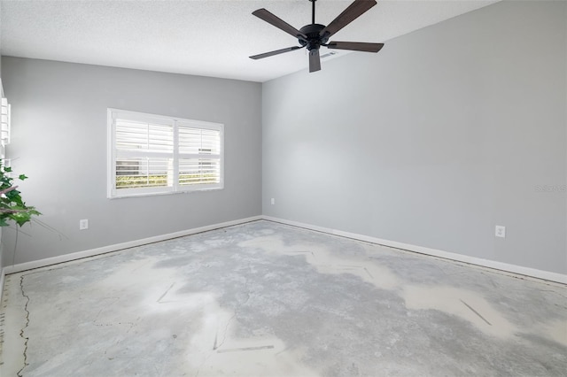 spare room with ceiling fan, baseboards, concrete floors, and a textured ceiling