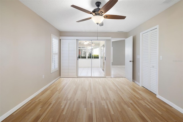 spare room featuring a ceiling fan, wood finished floors, baseboards, and a textured ceiling