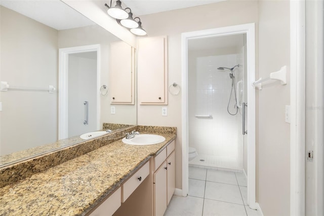 bathroom featuring tile patterned floors, toilet, tiled shower, baseboards, and vanity