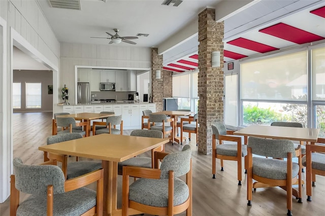 dining space with a wealth of natural light, visible vents, light wood-style flooring, and decorative columns