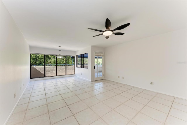 empty room featuring light tile patterned floors, a ceiling fan, and baseboards