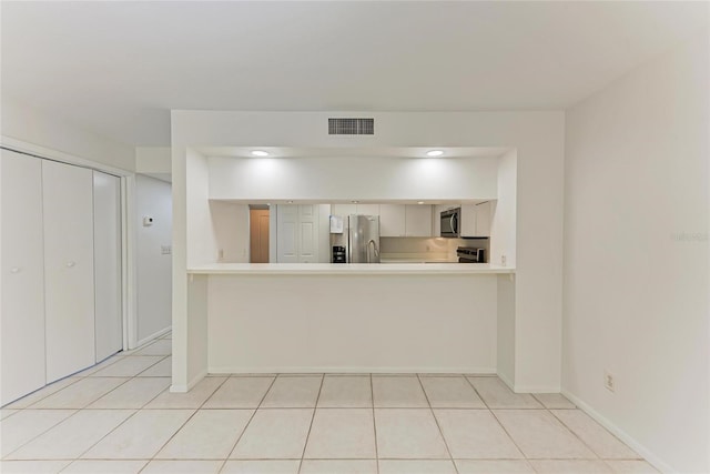 kitchen with visible vents, stainless steel appliances, a peninsula, light countertops, and light tile patterned floors