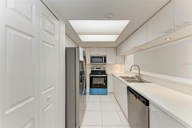 kitchen featuring light tile patterned floors, a sink, light countertops, white cabinets, and appliances with stainless steel finishes