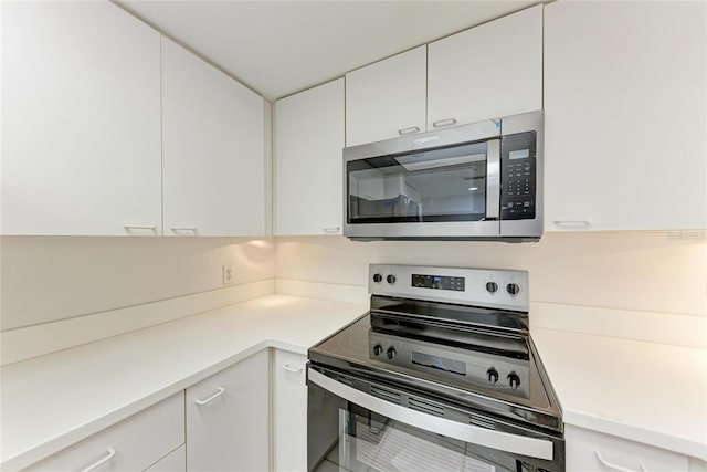 kitchen with appliances with stainless steel finishes, white cabinets, and light countertops