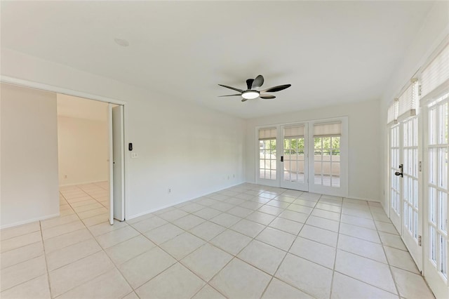 empty room with light tile patterned floors, french doors, baseboards, and ceiling fan