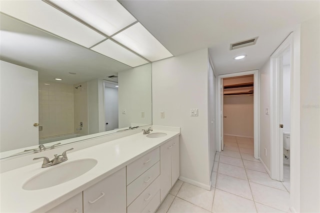 bathroom featuring tile patterned flooring, visible vents, double vanity, and a sink