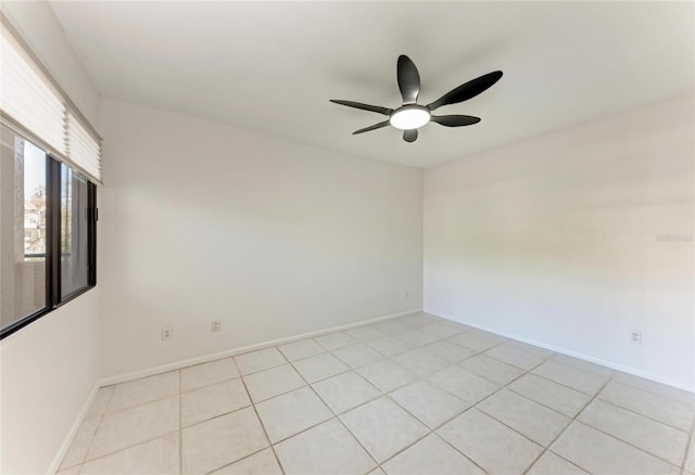 empty room with light tile patterned floors, a ceiling fan, and baseboards