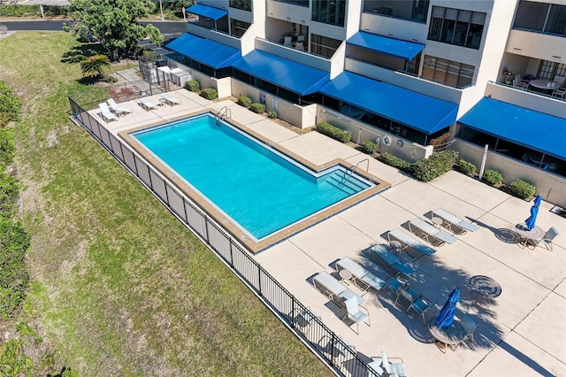 community pool with a patio area, grilling area, a lawn, and fence