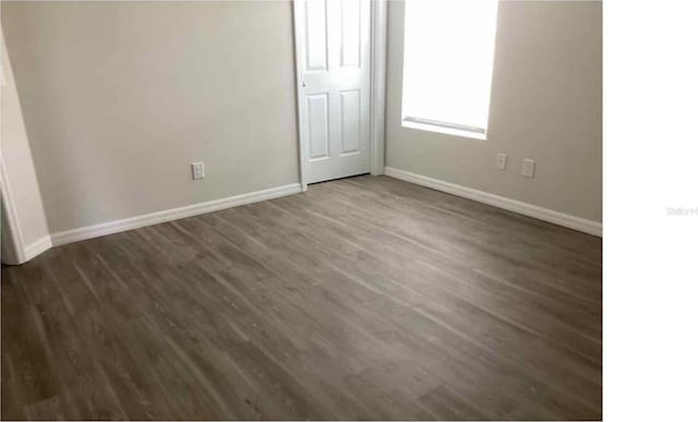 unfurnished bedroom with dark wood-type flooring and baseboards