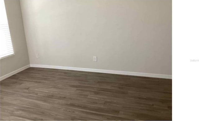 unfurnished room with dark wood-type flooring and baseboards