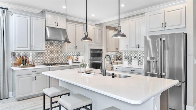 kitchen with a sink, under cabinet range hood, a kitchen breakfast bar, tasteful backsplash, and appliances with stainless steel finishes