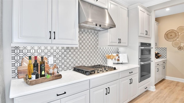 kitchen with stainless steel appliances, light countertops, under cabinet range hood, white cabinetry, and tasteful backsplash