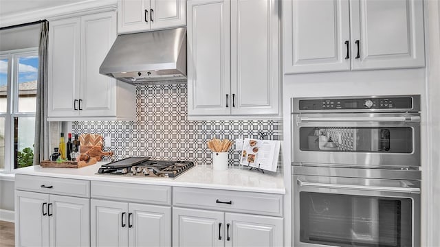 kitchen with under cabinet range hood, appliances with stainless steel finishes, white cabinetry, and light countertops